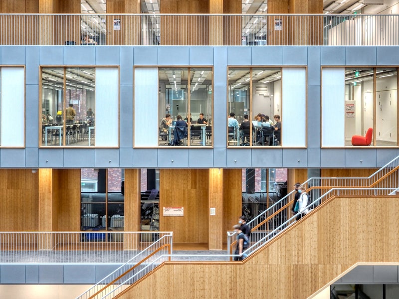 Zijaanzicht van een trap die langs de ramen van onderwijszalen in het NU-gebouw omhoog loopt
