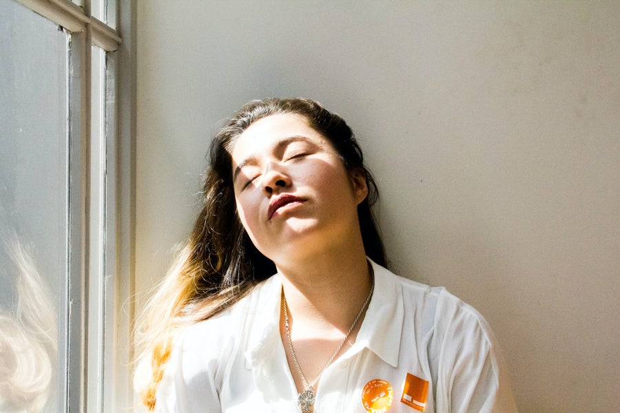 Woman in a white coat leans against a wall at the windowsill 