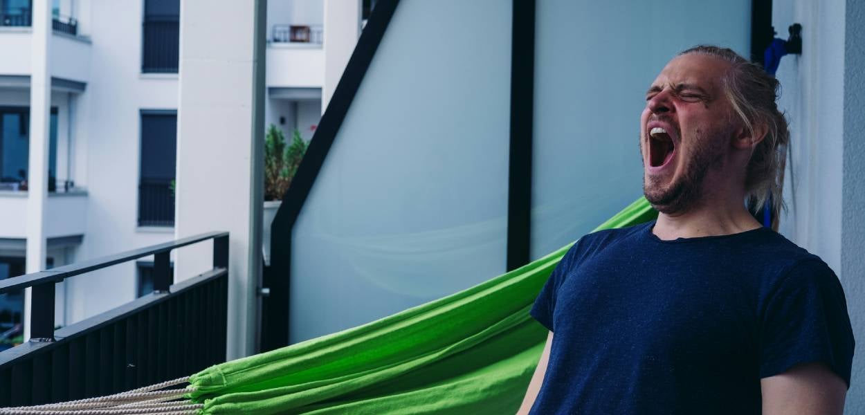 A man is yawning on his balcony.