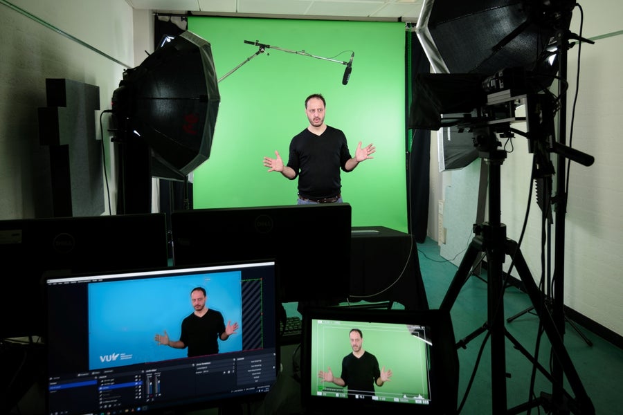 Docent voor een greenscreen in een ruimte met filmapparatuur en computerschermen