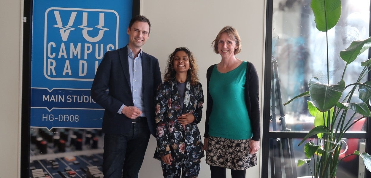 Jeroen Geurts, Sita Mohabir en Tirza Bosma posing in front of a VU Campus Radio banner