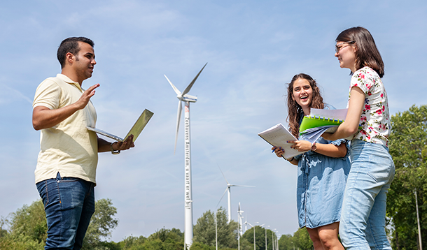 Drie studenten zijn buiten in overleg met op de achtergrond een windmolen