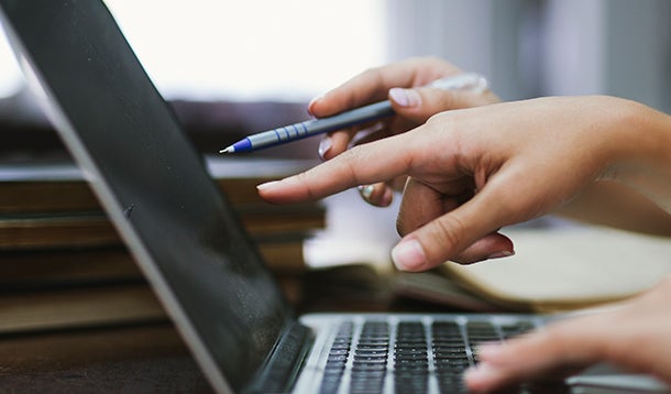 Two hands which are pointed at the screen of a laptop