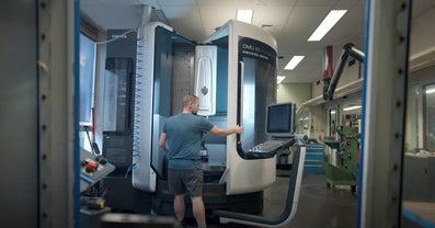 Een man bedient een geavanceerde machine in een technisch laboratorium.