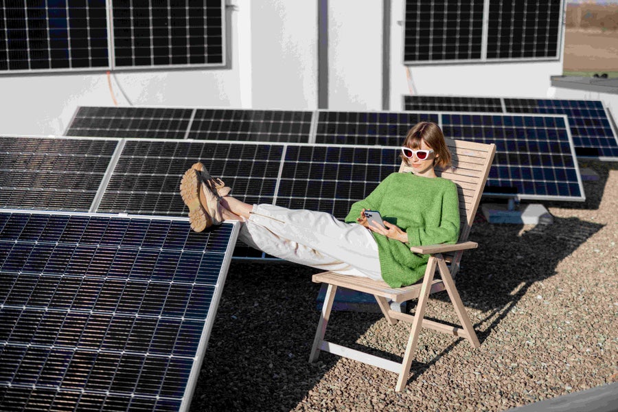 Vrouw met zonnebril zit op stoel nabij zonnepanelen