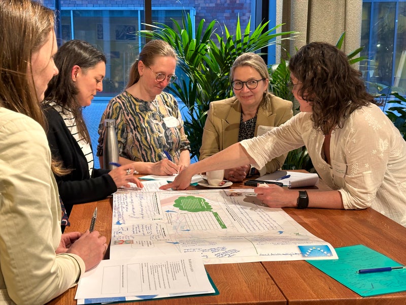 Vijf VU-onderzoekers buigen zich over papieren casus op tafel.