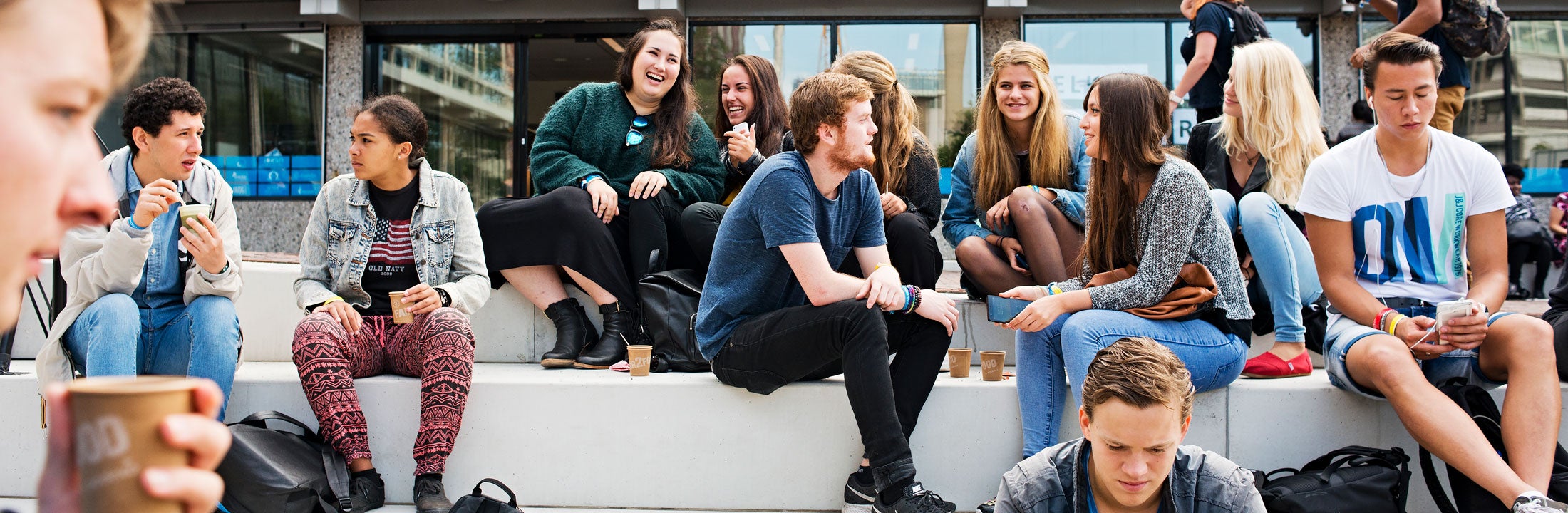 Studens having a break and sitting on stairs outside