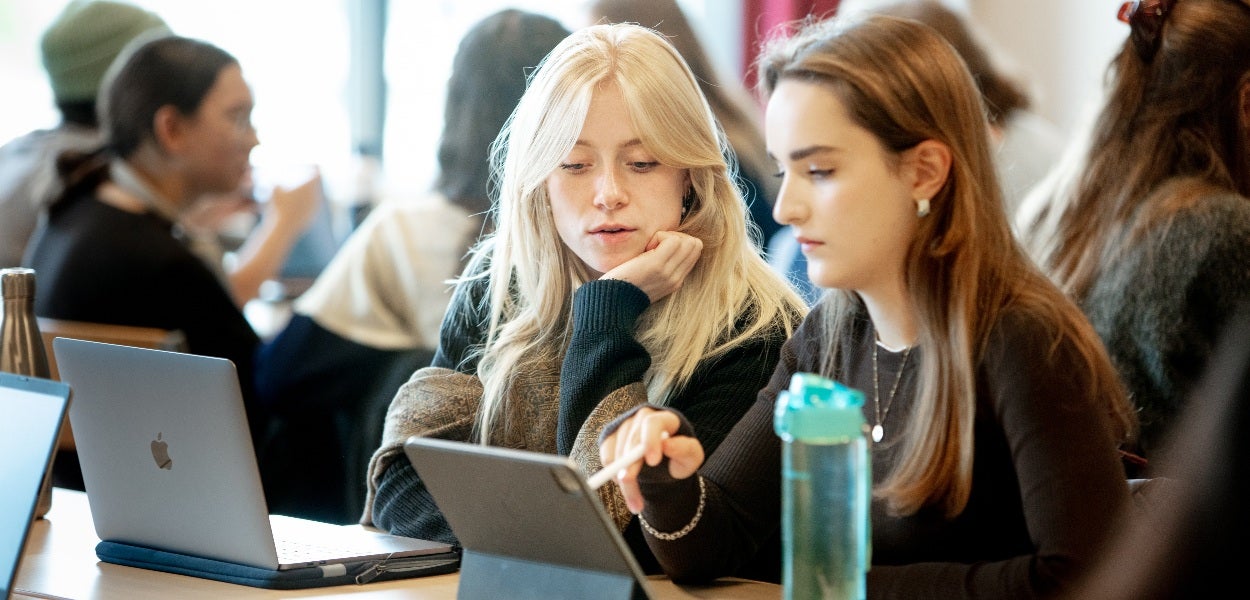 Two students look focused at a tablet.