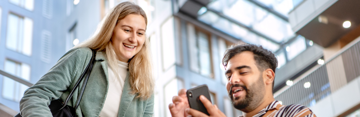 Twee mensen in VU-gebouw kijkend naar smartphone