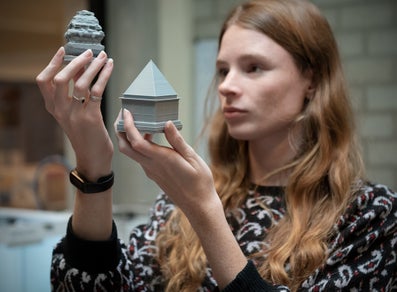 Vrouw houdt twee 3D geprinte voorwerpen in haar handen.