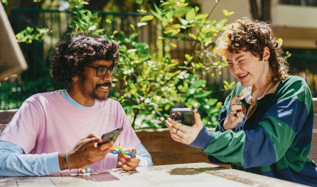 Two partners are laughing and showing something on their phones