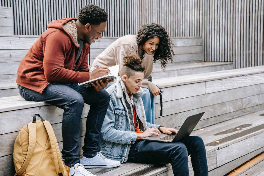 Drie personen op een trap met een laptop en een notitieboekje