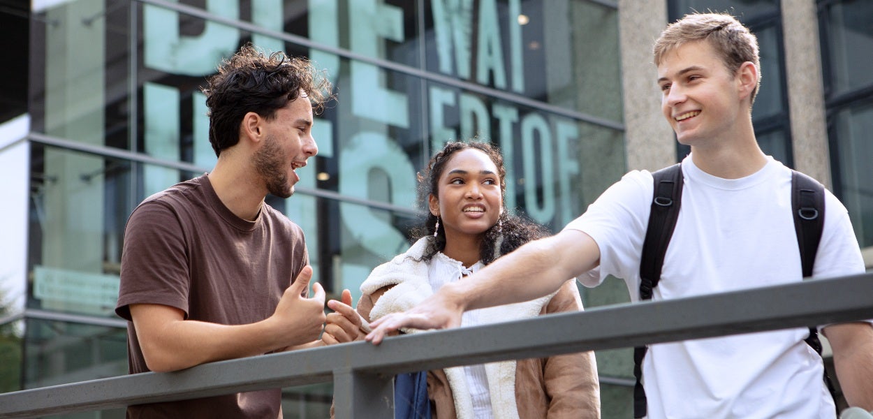 Drie studenten staan kletsend voor het hoofdgebouw van de Vrije Universiteit van Amsterdam. 