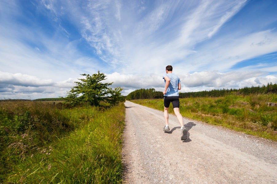 Een man is aan het hardlopen op een landweggetje.