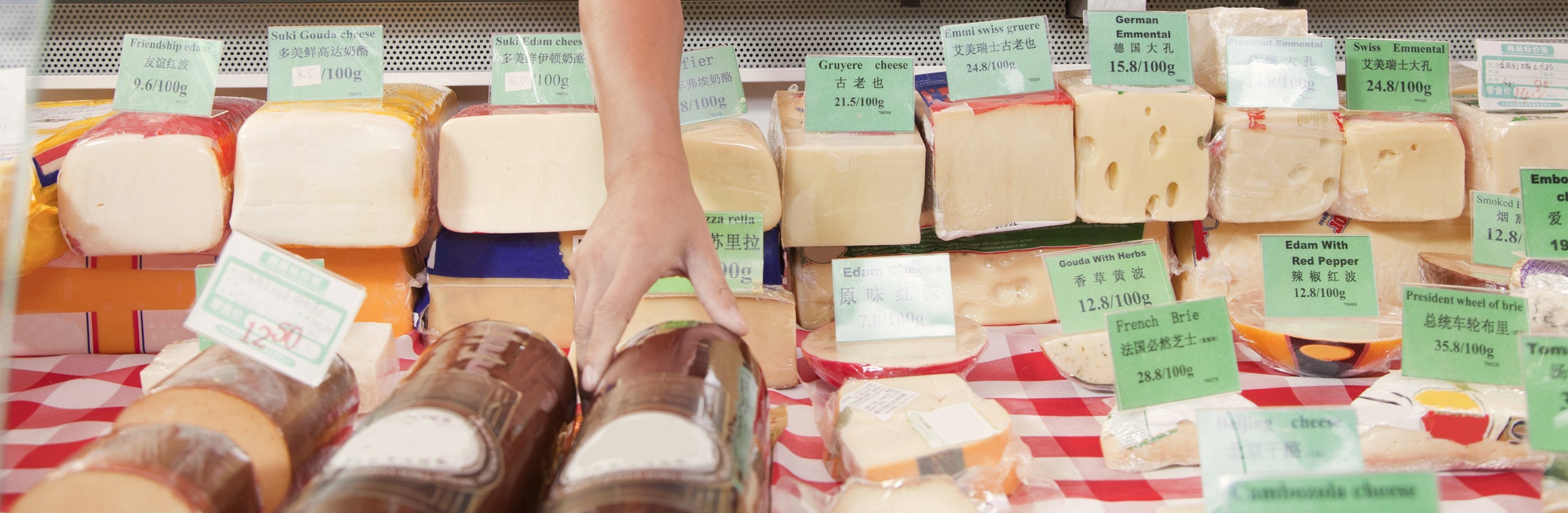 A cheese counter and a hand grabbing for cheese