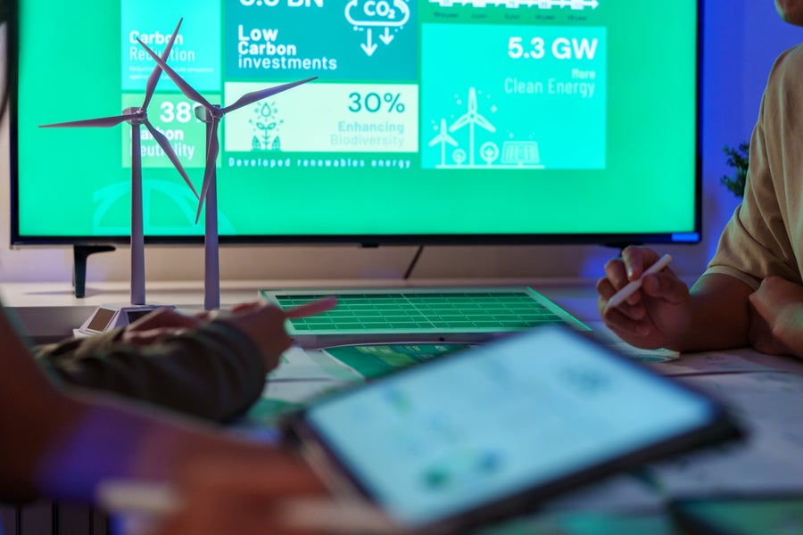 Beeldscherm met CO2-data achter miniatuur windmolens. 