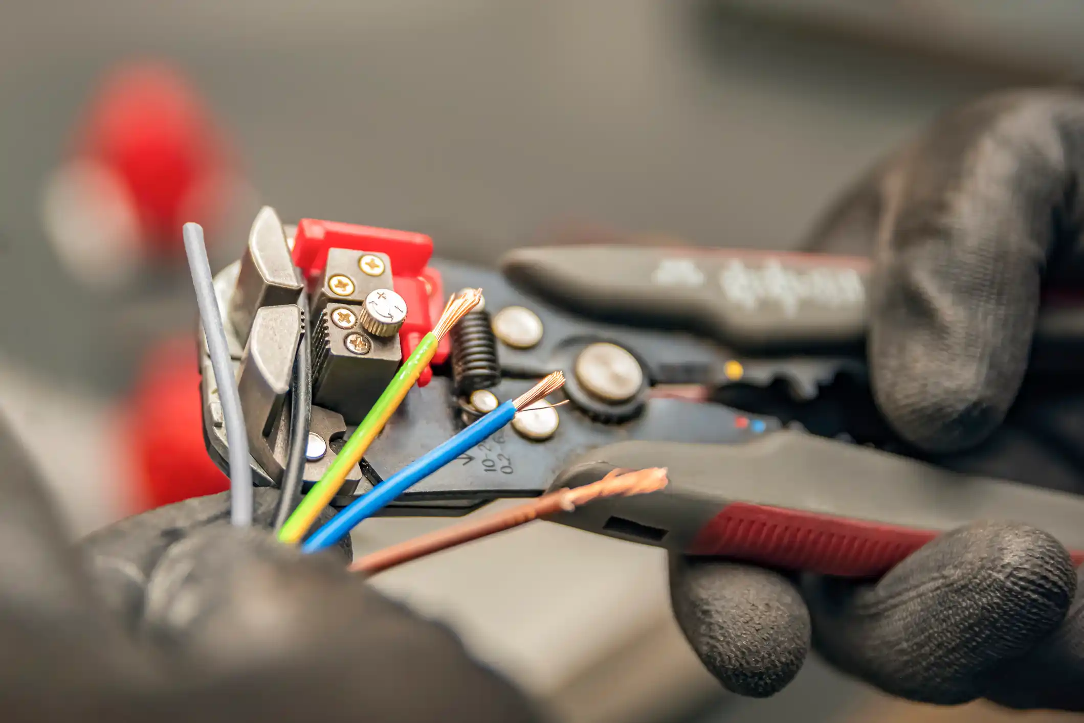The electrician cleans the protective insulation from the wire using a wire stripper. The process of connecting wires