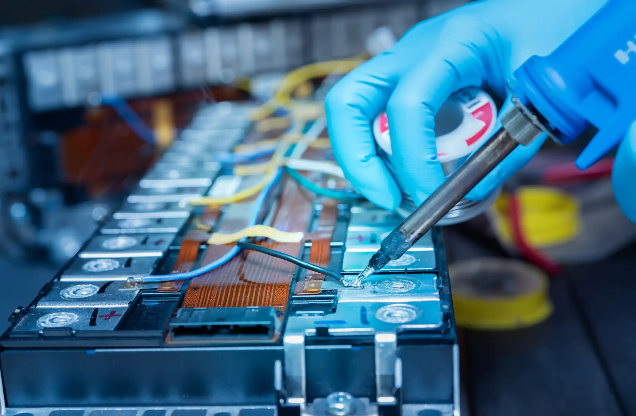 Repair module of Li-ion battery. Engineer hand holds soldering iron and tin-lead to solder electronic board.