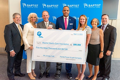 Florida Power & Light and Baptist representatives holding check