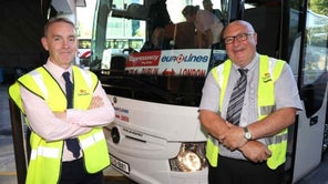 Two men stand in front of an Expressway Eurolines bus