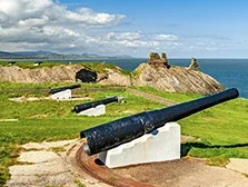 View of cliffs and seascape, old black cannons, and Black Castle ruins, South Quay, Co. Wicklow, Ireland.