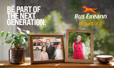 The image is a part of a recruitment campaign for Bus Éireann. The central focus is on a windowsill where two framed photographs are prominently displayed. The first photo shows a man in a suit and a young girl, standing in front of a Bus Éireann bus. The man is the grandfather of the girl; he has his arm around her. The second photo shows the same girl from the first photo, but now older, wearing a red Bus Éireann uniform jacket.