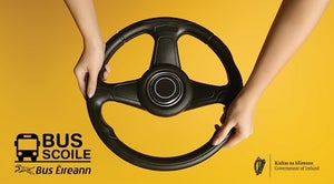 A close-up image features a black steering wheel held by two hands against a bright yellow background.