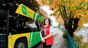 Image of female driver standing in from of yellow and green bus with 187 on its scroll