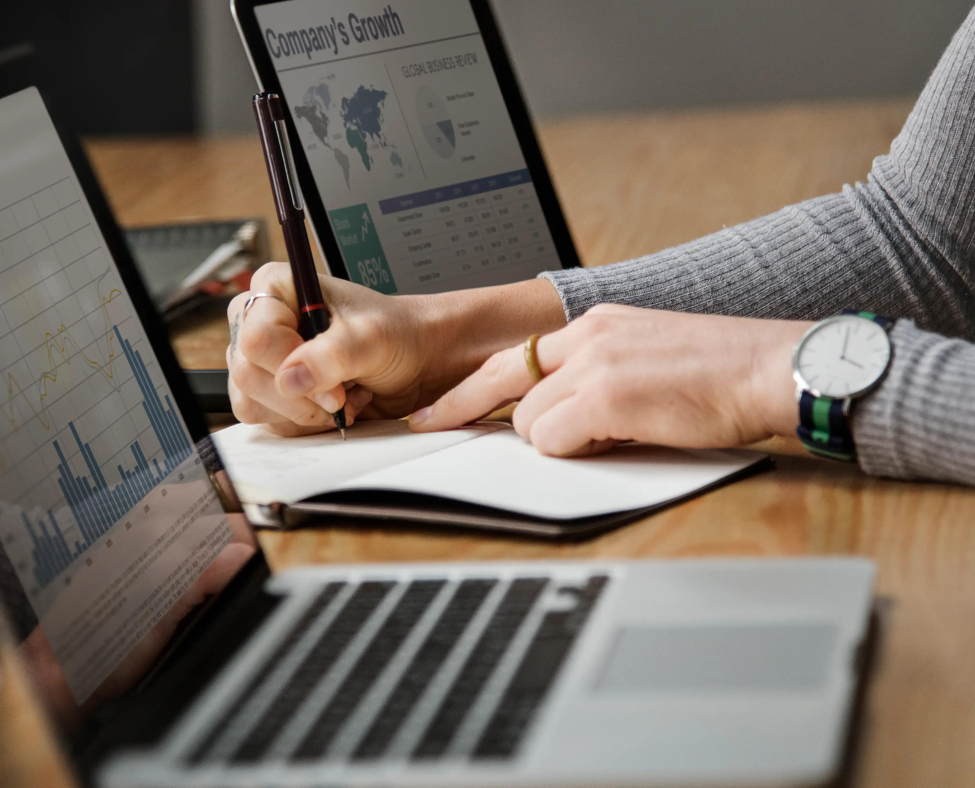 En la fotografía, pantalla de laptop mostrando datos y una persona escribe al lado de este. Esto representa la función de los marketers en integrar data storytelling.