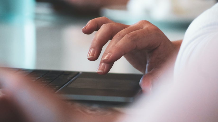 A woman’s hand above a laptop