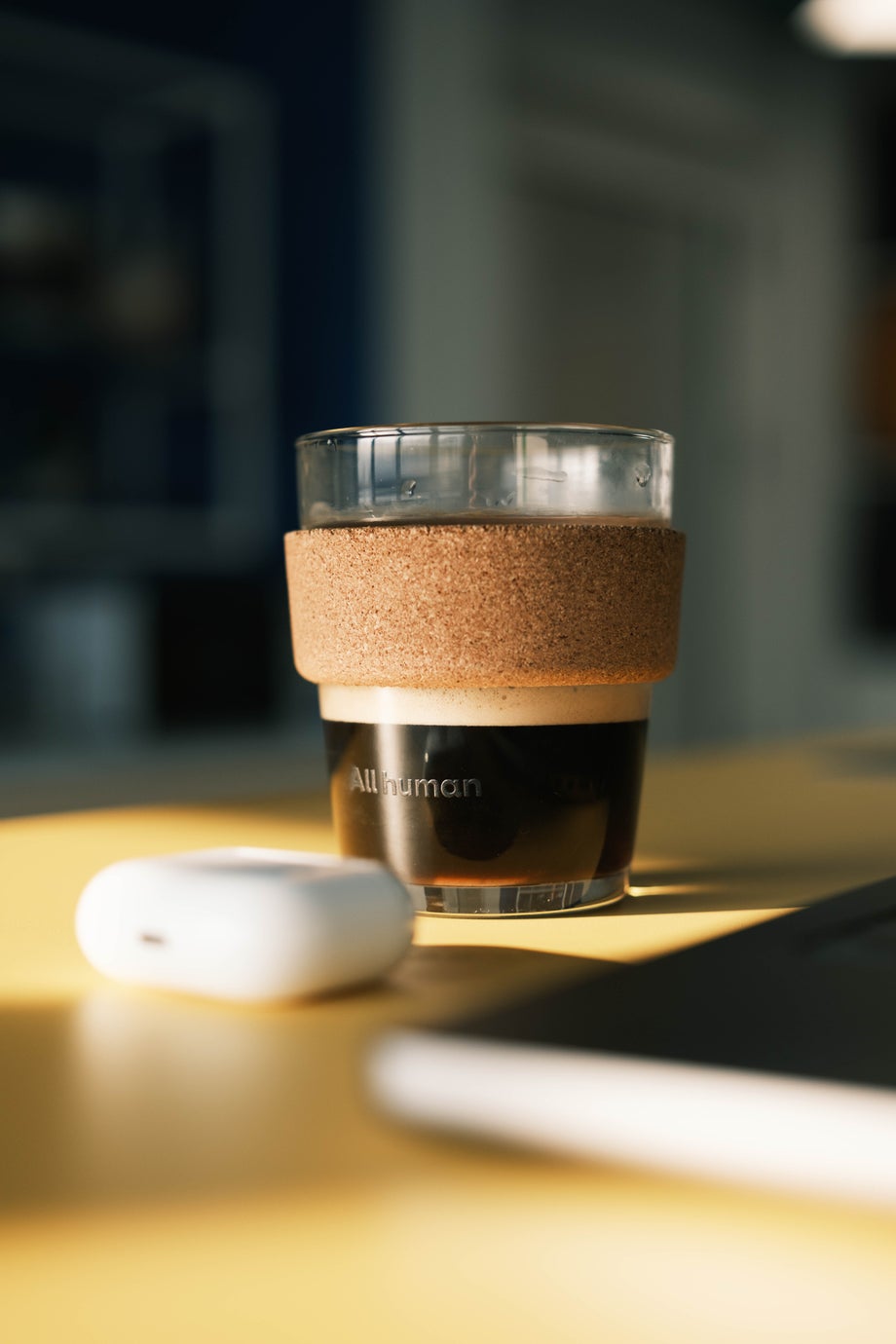 An All human branded coffee cup sits on a desk