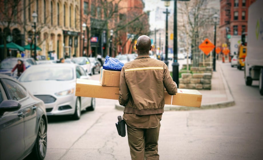 A delivery person carries multiple cardboard boxes