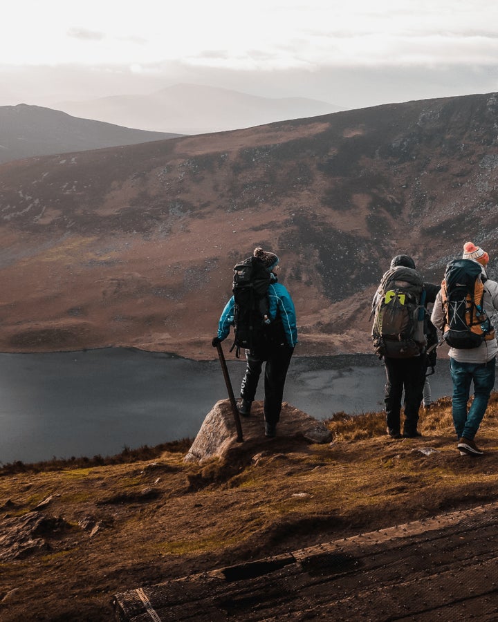 Hikers discovering Ireland on a mountain overlooking a lake