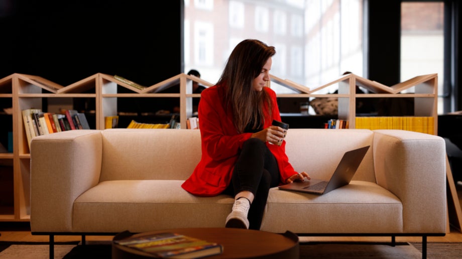 A woman in a red coat sitting on a couch in the office