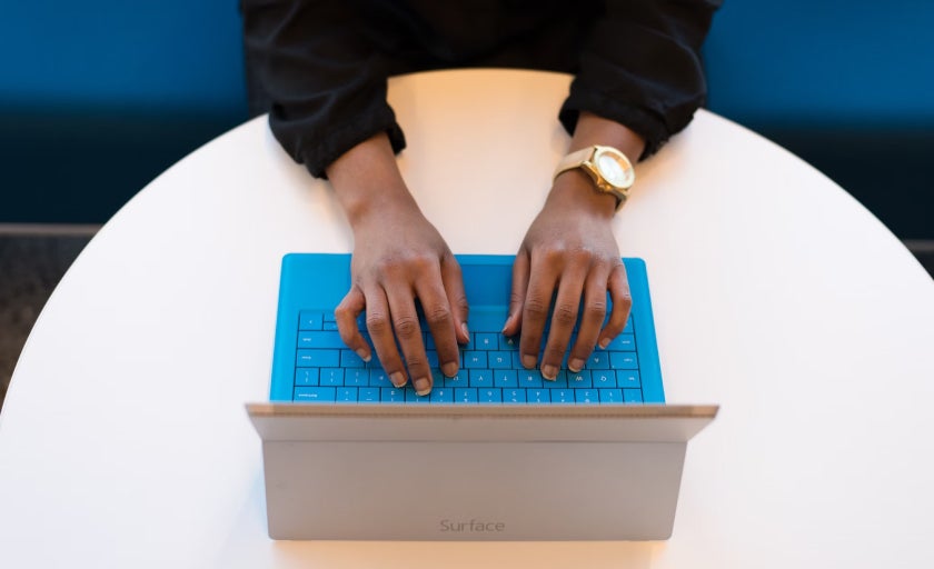 A person types on a blue kepyboard on a wireless tablet