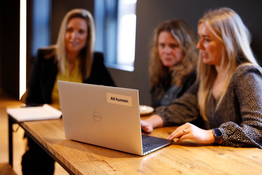 Three women look at a laptop screen 