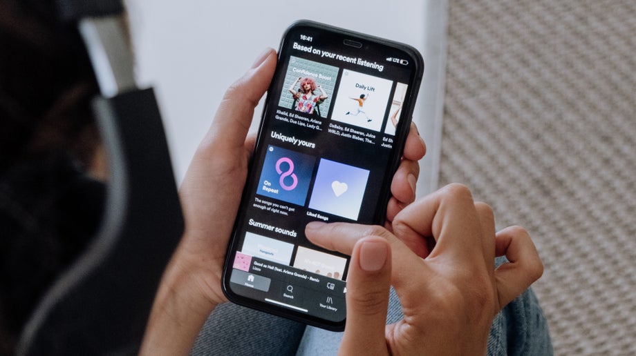 A closeup of an individual using their mobile phone. Spotify’s personalised playlists are shown.