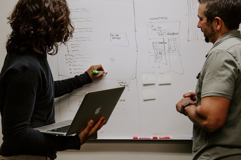 Two people plan on a whiteboard 