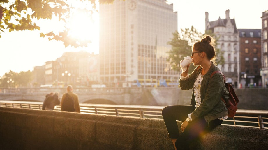 A young woman enjoys a coffee near the Liffey river