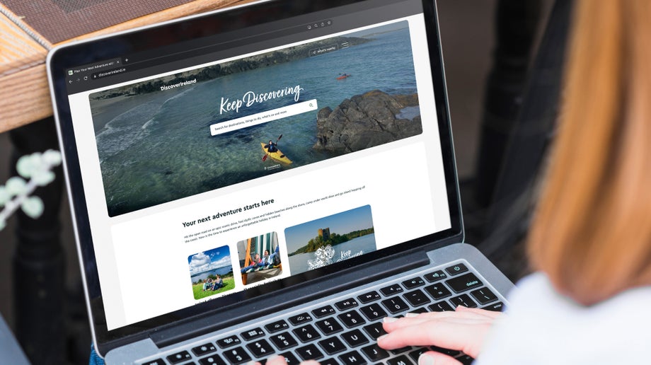 An individual is viewing Discover Ireland’s landing page from their laptop screen.
