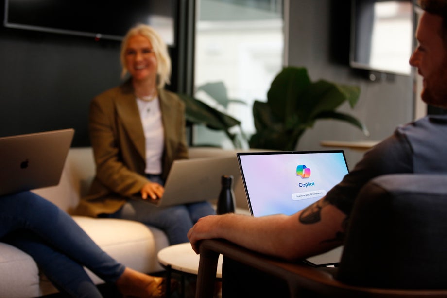 A group of people chat with CoPilot appearing on a laptop screen