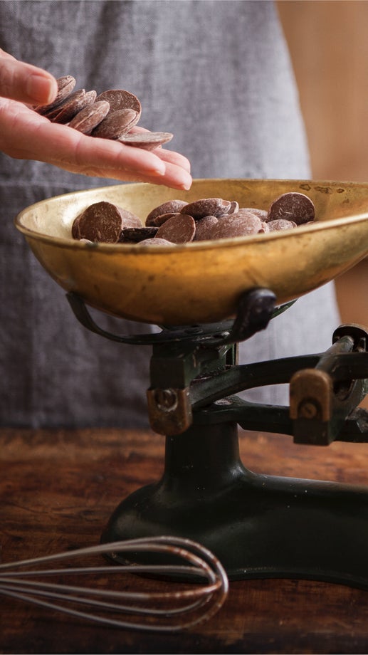 A cook picks up the right amount of chocolate for her recipe