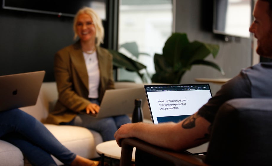 Colleagues laughing together while working on laptops 