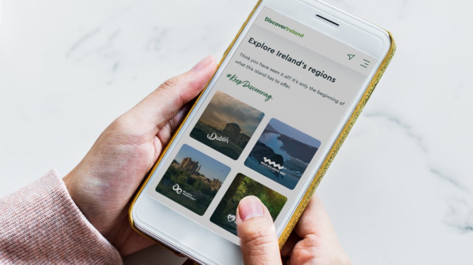An individual is visiting the Discover Ireland website on their mobile phone. There are options on their device to learn about Ireland through Visit Dublin, Wild Atlantic Way, Ireland’s Ancient East and Ireland’s Hidden Heartlands.
