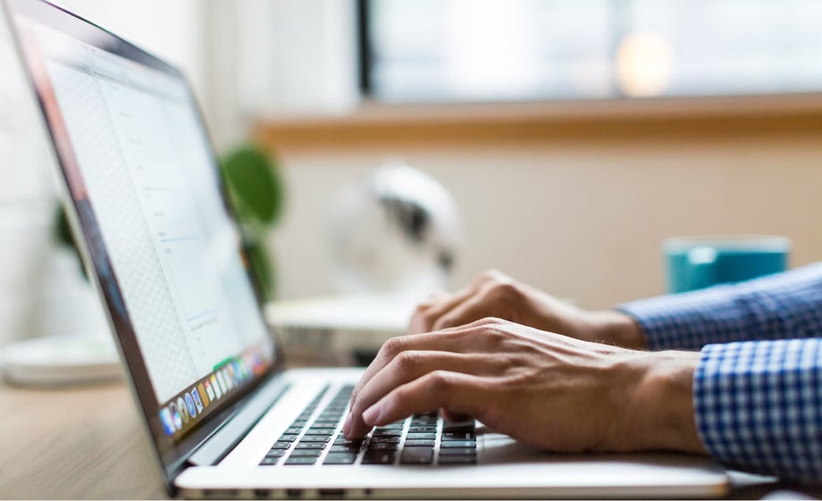 A person types on a laptop 