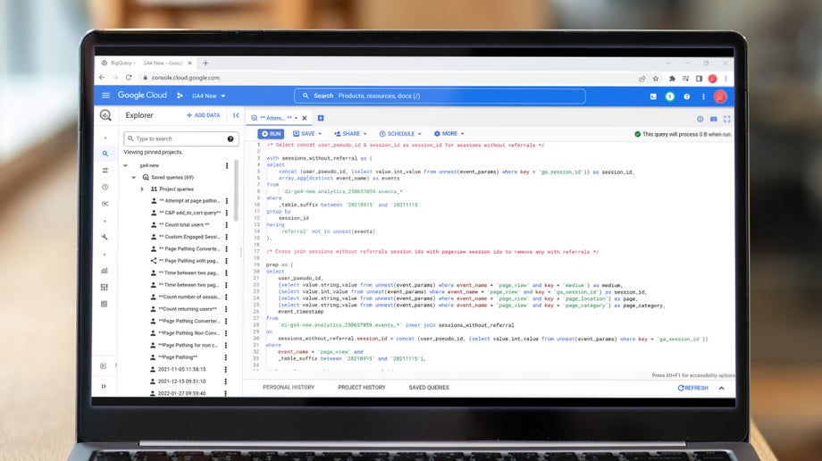 A close up of a laptop screen showing Google Analytics 4 Big Query integration. There is a list of project queries followed by lines of code.