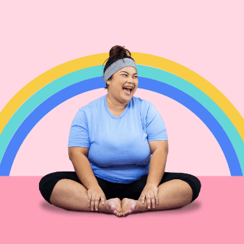 woman smiles while doing yoga with a rainbow behind