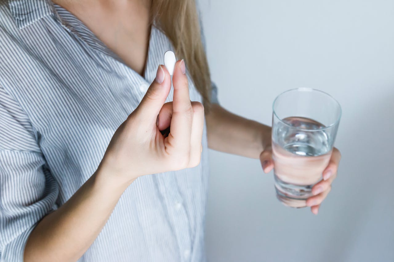 Close-up of a person taking propranolol medication with water