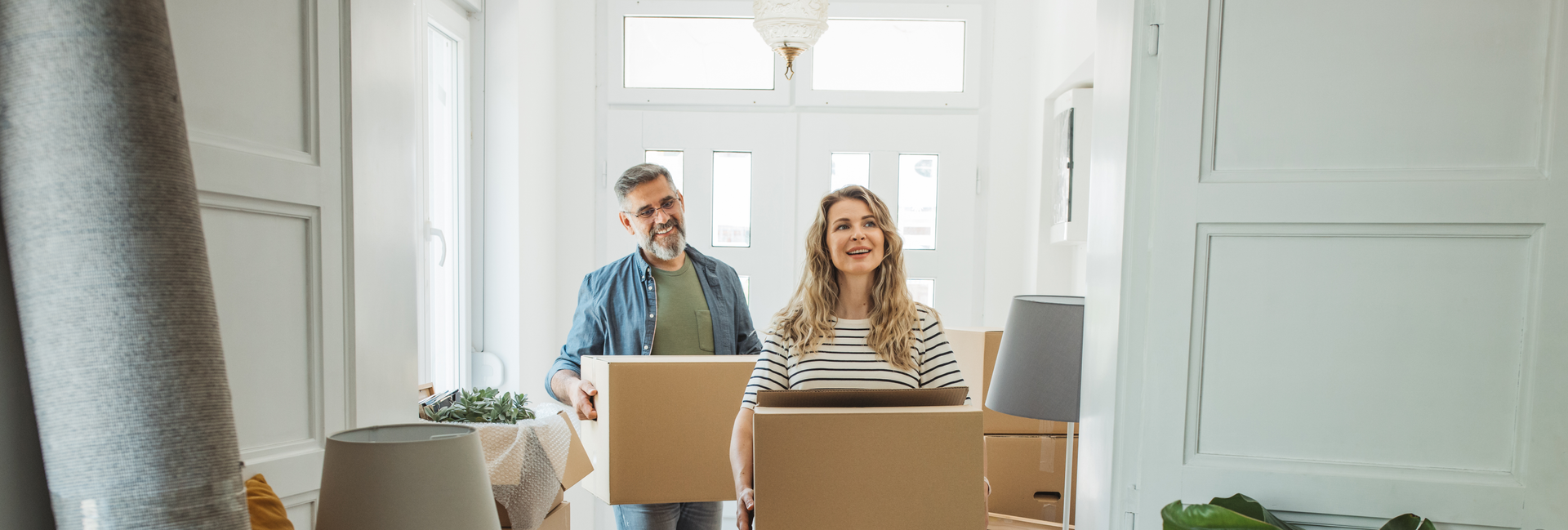 Man and woman carry boxes into new house