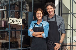 Business owners stand next to open sign